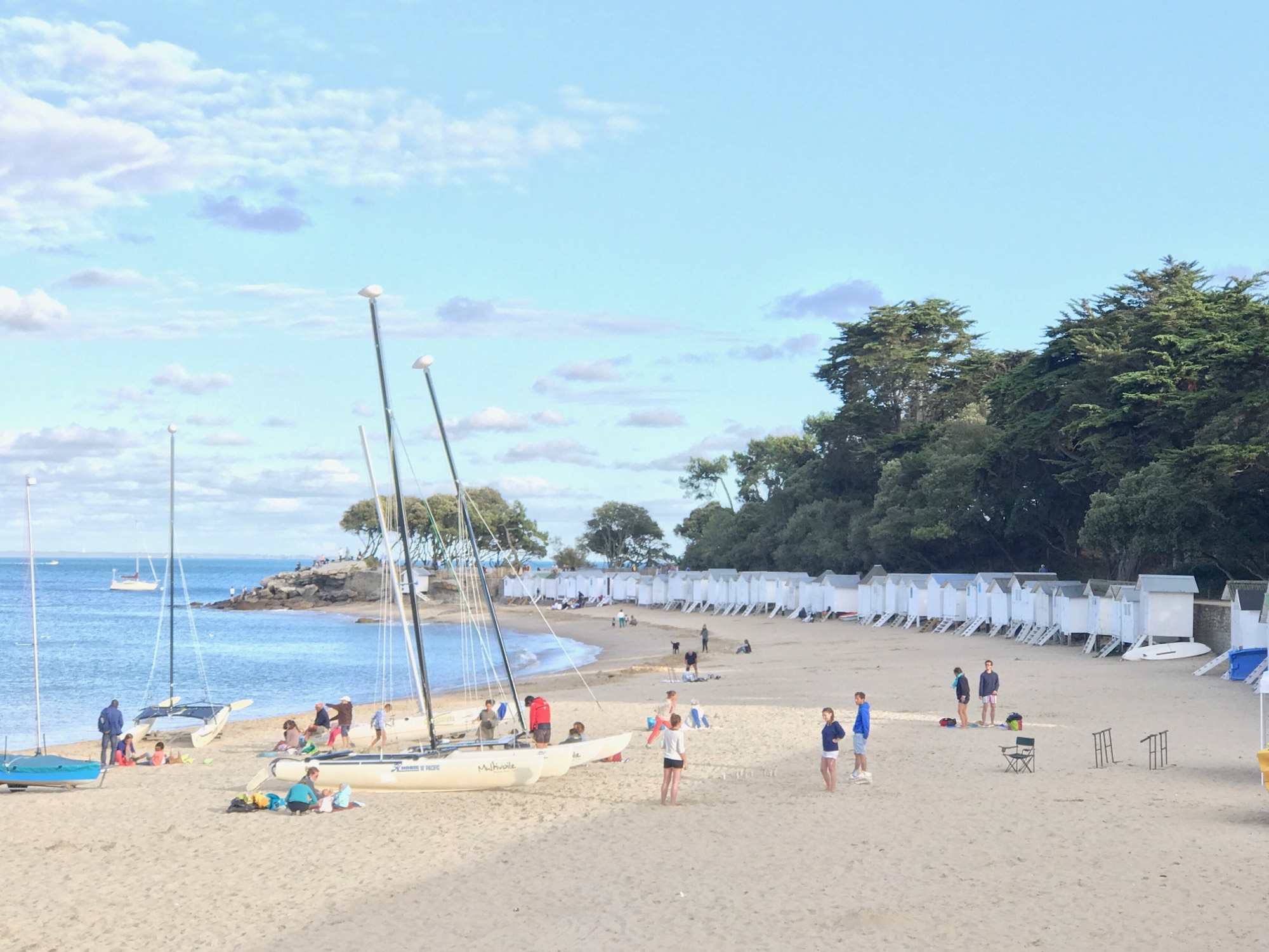 Plages des Dames with sailing dinghies on the sand and beach huts along the shore